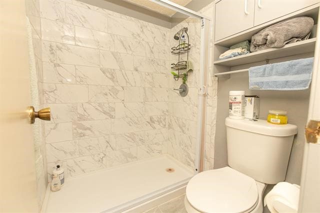 bathroom featuring tiled shower and toilet