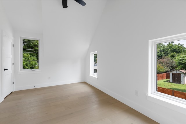 spare room with a healthy amount of sunlight, light hardwood / wood-style flooring, vaulted ceiling, and ceiling fan