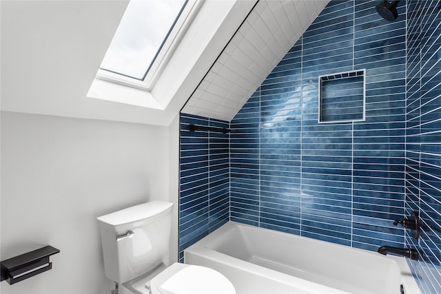 bathroom featuring tiled shower / bath combo, toilet, and lofted ceiling with skylight