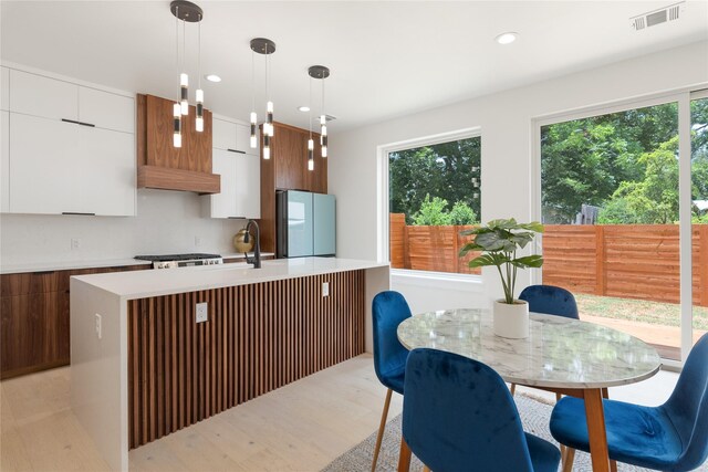 kitchen featuring decorative light fixtures, white cabinets, refrigerator, and plenty of natural light