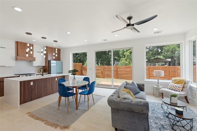 kitchen featuring decorative light fixtures, a breakfast bar, light wood-type flooring, fridge, and a center island with sink