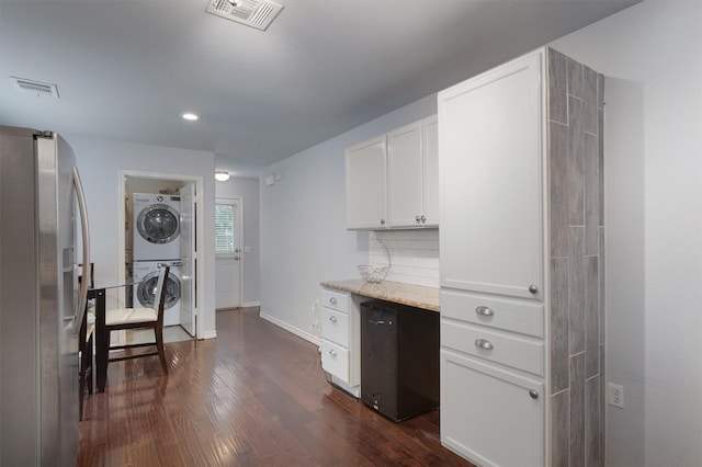 kitchen featuring stacked washer / drying machine, decorative backsplash, white cabinetry, dark wood-type flooring, and stainless steel fridge with ice dispenser