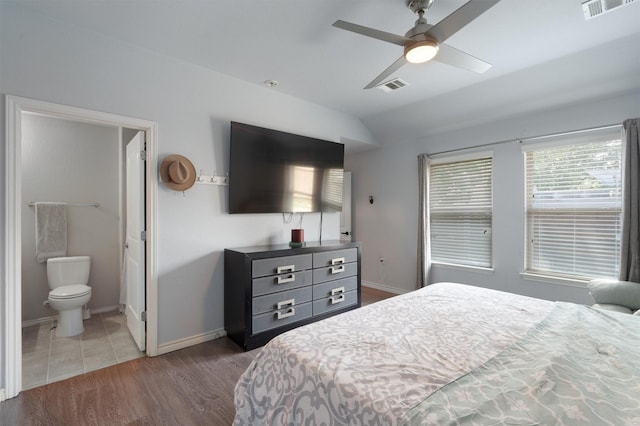 bedroom with ceiling fan, dark wood-type flooring, connected bathroom, and lofted ceiling