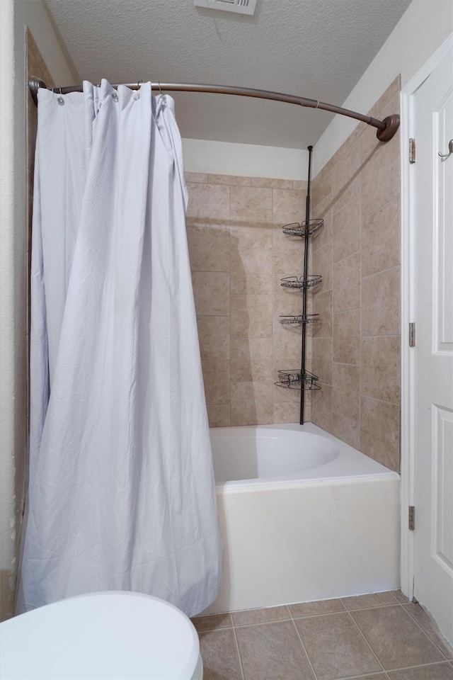 bathroom featuring a textured ceiling, tile patterned flooring, and shower / bath combo