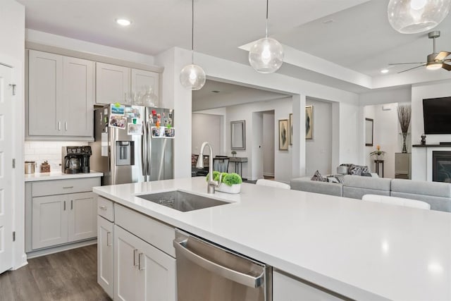 kitchen with pendant lighting, sink, stainless steel appliances, dark hardwood / wood-style floors, and tasteful backsplash