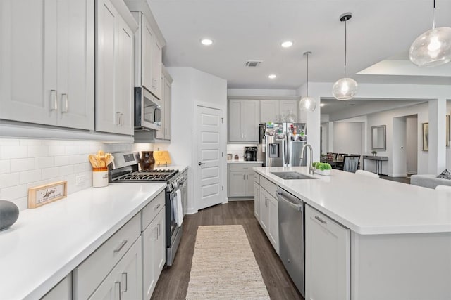 kitchen featuring dark hardwood / wood-style floors, sink, hanging light fixtures, stainless steel appliances, and a spacious island