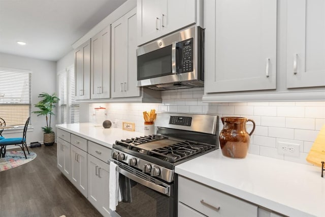 kitchen featuring dark wood-type flooring, stainless steel appliances, backsplash, and white cabinets