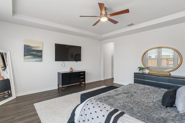 bedroom featuring a raised ceiling, dark hardwood / wood-style floors, and ceiling fan