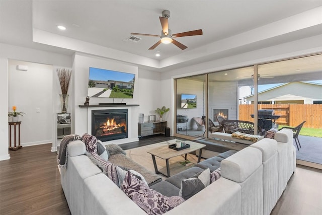 living room with ceiling fan, wood-type flooring, and a tray ceiling