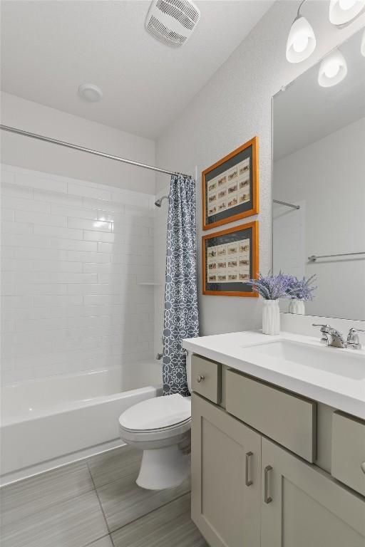 full bathroom with vanity, shower / tub combo, and toilet