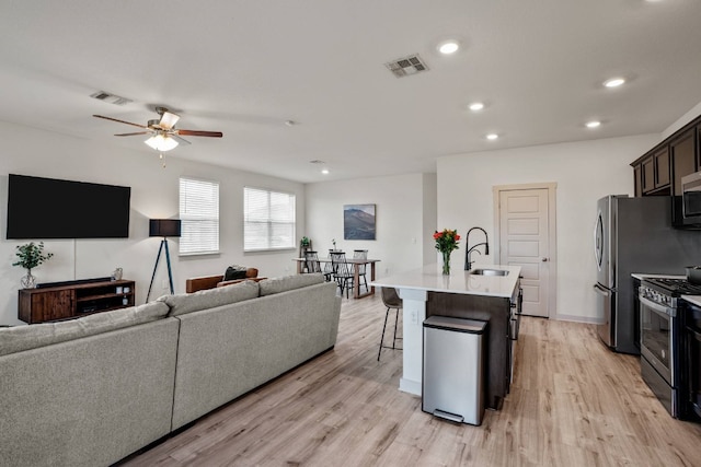 living room with ceiling fan, sink, and light wood-type flooring