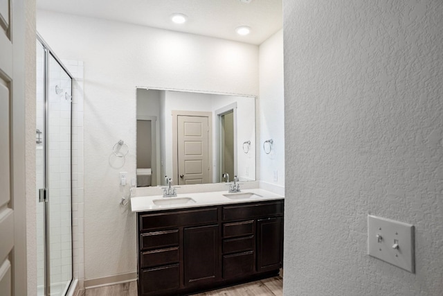 bathroom featuring a shower with shower door, wood-type flooring, and vanity