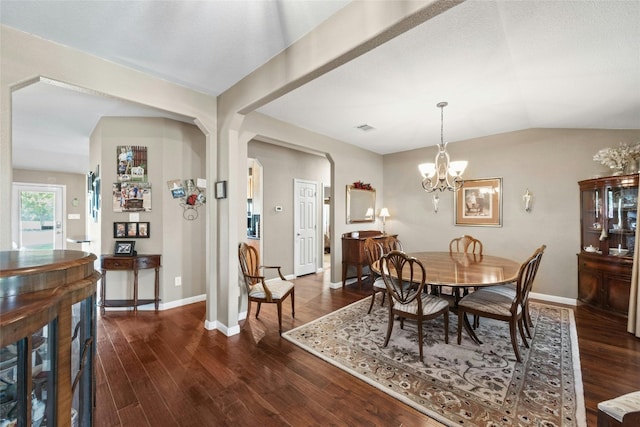 dining area with dark wood-type flooring, lofted ceiling, and an inviting chandelier