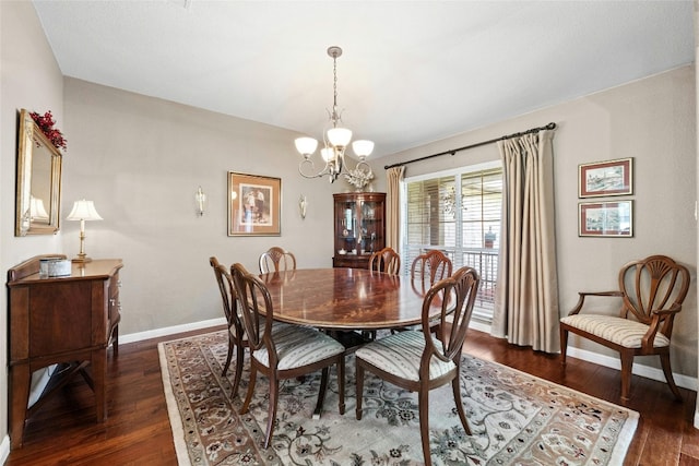 dining area with dark hardwood / wood-style floors and an inviting chandelier