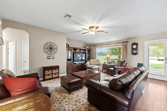 living room featuring ceiling fan, lofted ceiling, a textured ceiling, and light hardwood / wood-style flooring