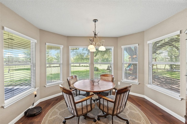 dining space featuring a chandelier, dark wood-type flooring, a healthy amount of sunlight, and a textured ceiling