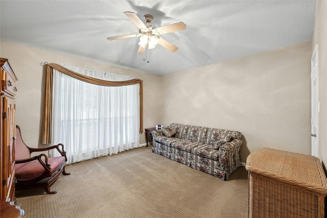 living area featuring a textured ceiling, ceiling fan, and light carpet