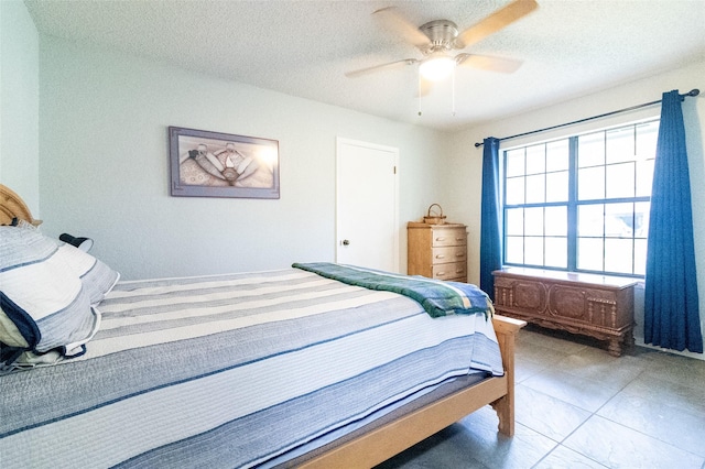 bedroom with ceiling fan, tile patterned floors, and a textured ceiling