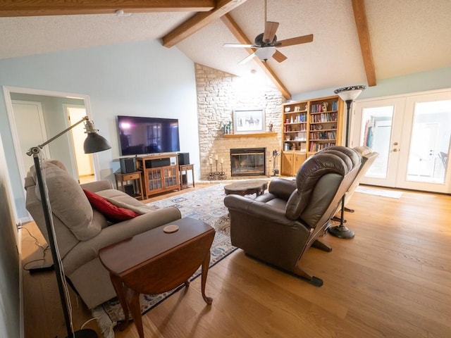 living room with a large fireplace, light hardwood / wood-style floors, a textured ceiling, beam ceiling, and french doors