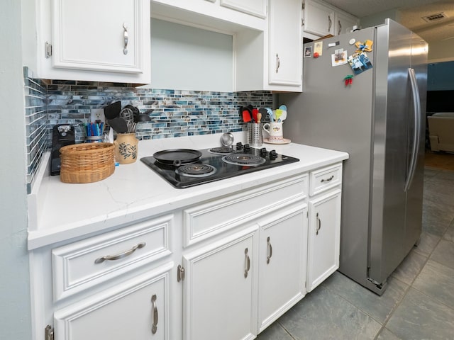 kitchen with white cabinetry, black electric stovetop, stainless steel fridge, and decorative backsplash