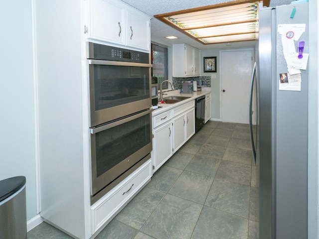 kitchen with backsplash, appliances with stainless steel finishes, sink, and white cabinets