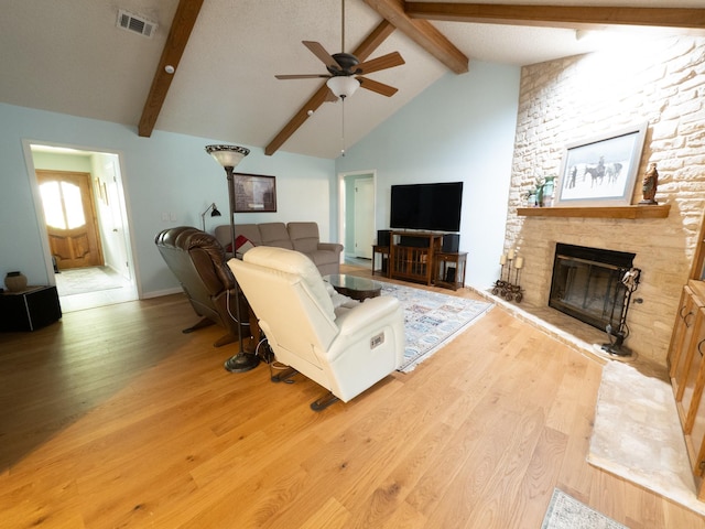 living room with high vaulted ceiling, a fireplace, beamed ceiling, ceiling fan, and light wood-type flooring