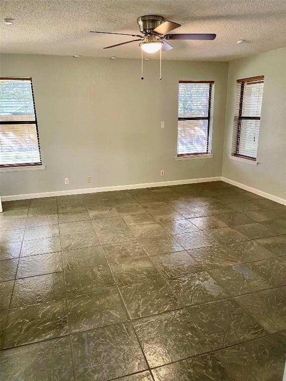 spare room with ceiling fan, a textured ceiling, and a healthy amount of sunlight