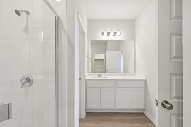 bathroom featuring vanity, wood-type flooring, and a tile shower