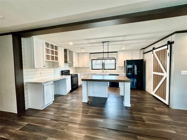 kitchen featuring a barn door, black appliances, white cabinets, and dark hardwood / wood-style flooring