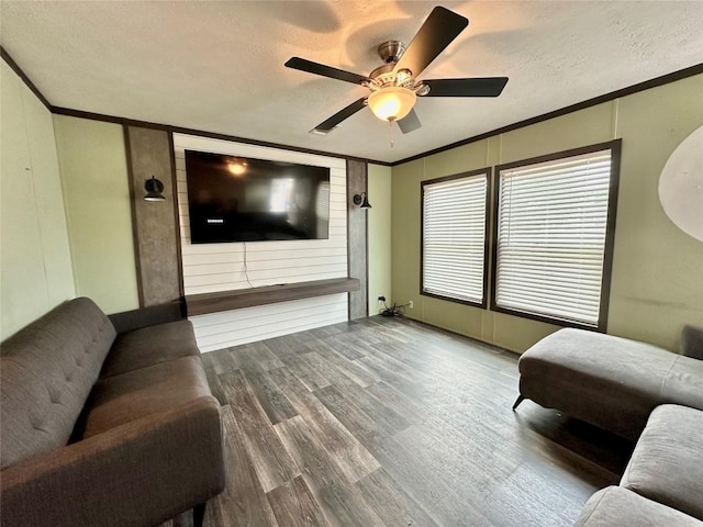 living room featuring hardwood / wood-style flooring, ornamental molding, ceiling fan, and a textured ceiling