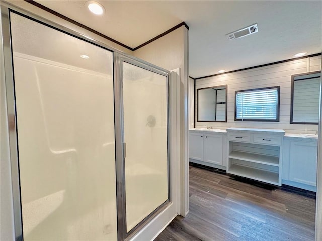 bathroom featuring vanity, hardwood / wood-style flooring, a shower with door, and crown molding