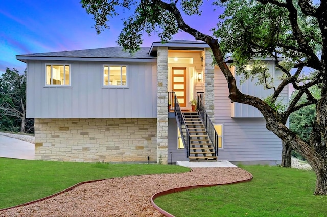 21201 Norris Cv, Lago Vista, TX 78645 - modern home featuring board and batten siding, stone siding, stairway, a front yard, and a shingled roof
