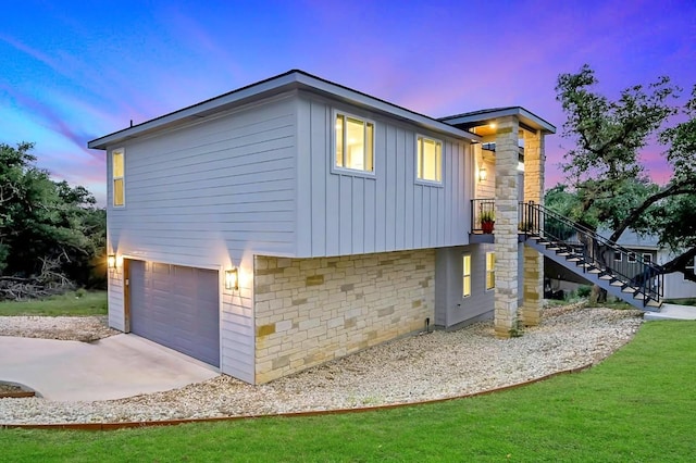 property exterior at dusk with a garage, stone siding, stairway, and board and batten siding