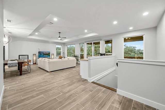21201 Norris Cv, Lago Vista, TX 78645 - living room featuring a tray ceiling, light wood-style flooring, a ceiling fan, recessed lighting, and baseboards