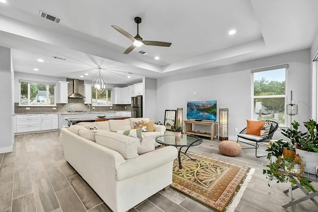 21201 Norris Cv, Lago Vista, TX 78645 - living area featuring a raised ceiling, healthy amount of natural light, a ceiling fan, light wood-style floors, and recessed lighting