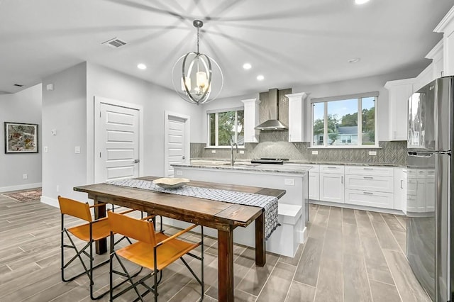 21201 Norris Cv, Lago Vista, TX 78645 - kitchen featuring freestanding refrigerator, wall chimney range hood, decorative backsplash, white cabinets, and recessed lighting