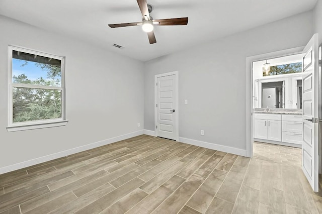 21201 Norris Cv, Lago Vista, TX 78645 - unfurnished bedroom featuring a sink, light wood finished floors, baseboards, and ensuite bath