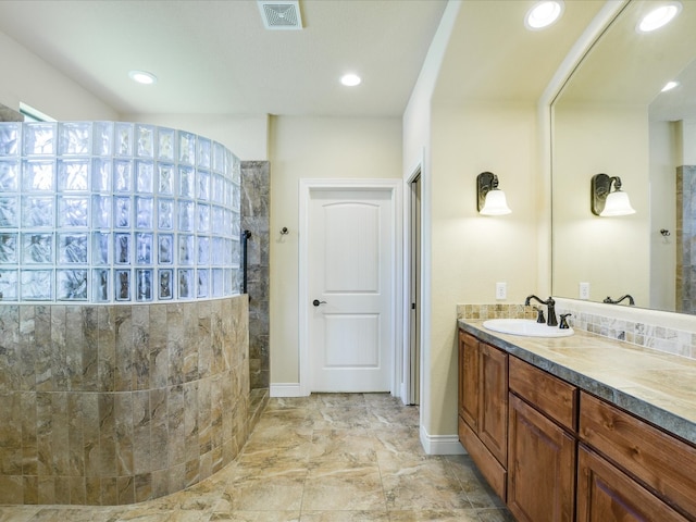 bathroom featuring tiled shower, tile flooring, and large vanity