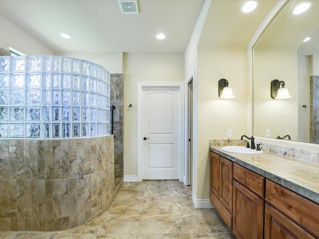 bathroom featuring a walk in shower, double vanity, recessed lighting, and baseboards