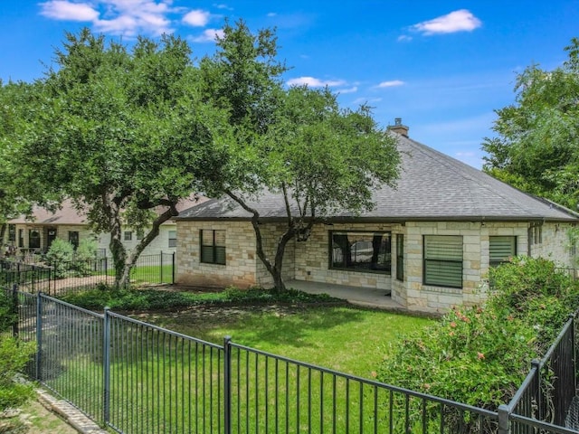 back of property with stone siding, a shingled roof, a chimney, and a patio