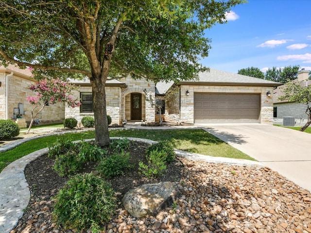 view of front facade with stone siding, concrete driveway, an attached garage, and central air condition unit