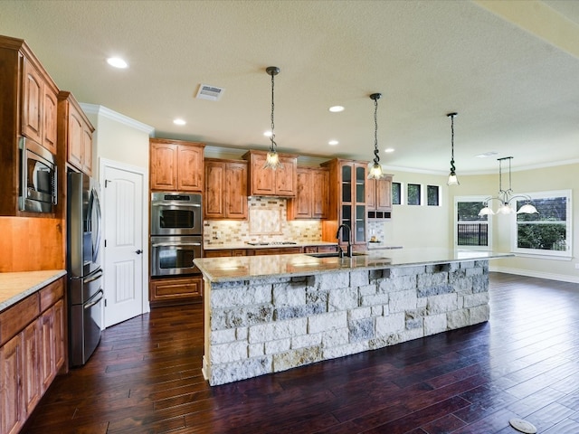 kitchen with dark hardwood / wood-style floors, crown molding, a spacious island, backsplash, and appliances with stainless steel finishes