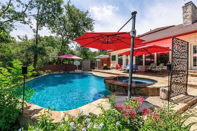 view of pool with a patio area, fence, and a pool with connected hot tub