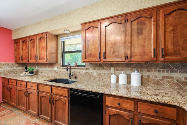 kitchen with light stone counters, black dishwasher, backsplash, brown cabinetry, and a sink