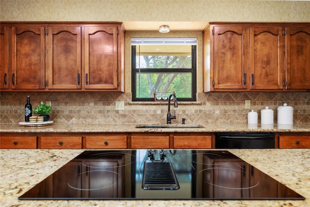 kitchen featuring black appliances, backsplash, a sink, and light stone countertops