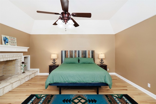 bedroom with a fireplace with raised hearth, wood finished floors, and baseboards