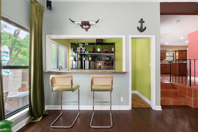 bar featuring bar, wood finished floors, and baseboards