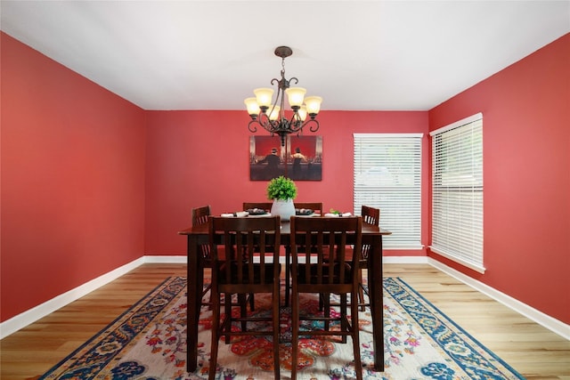 dining area with light wood-style floors, baseboards, and an inviting chandelier