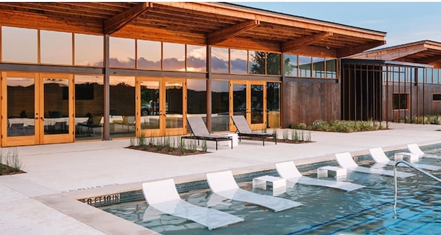 pool at dusk featuring a patio area and french doors