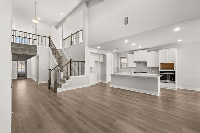 unfurnished living room featuring dark hardwood / wood-style floors, a towering ceiling, and sink